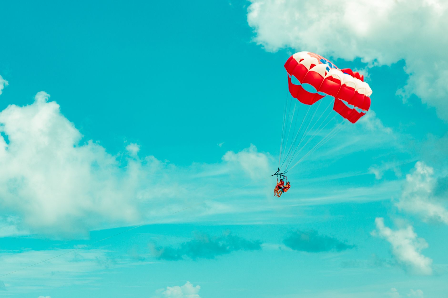 Parasailing na turkusowych wodach morskich, osoba schodzą na spadochronie w powietrzu