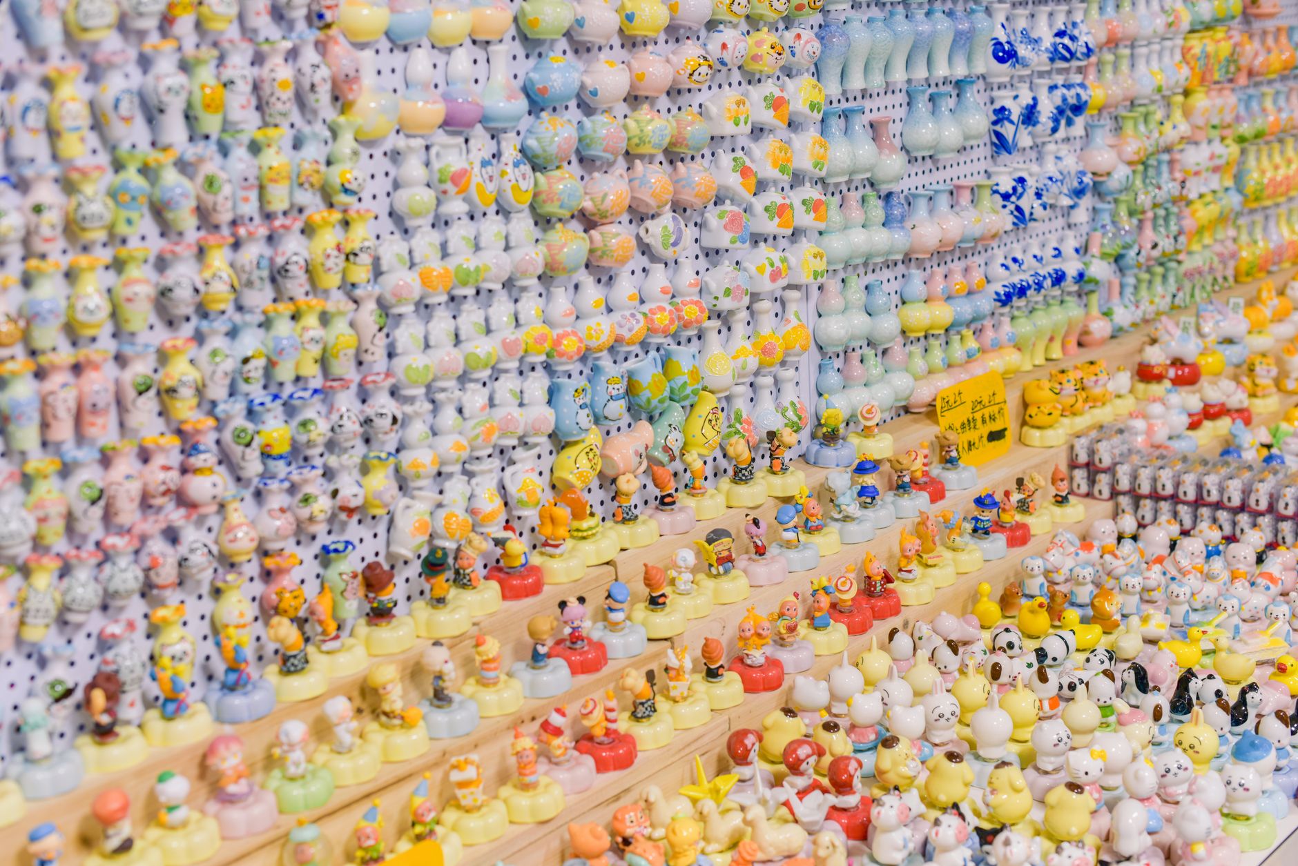 Regał pełen kolorowych miniaturowych figurek na białych półkach pegboard, ułożonych w rzędy od góry do dołu.