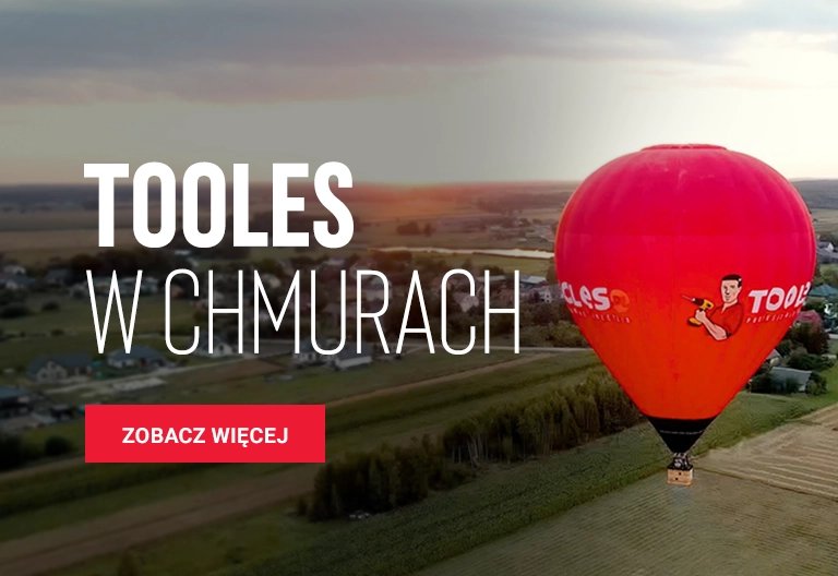 Czerwony balon na gorące powietrze unoszący się nad krajobrazem wiejskim z tekstem TOOLES w chmurach